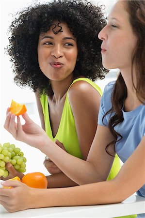 Close-up of two female friends eating fruits Photographie de stock - Premium Libres de Droits, Code: 6108-06907418