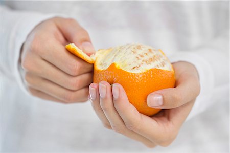 Close-up of a woman's hand peeling an orange Foto de stock - Sin royalties Premium, Código: 6108-06907419