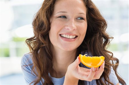 simsearch:6108-06904818,k - Close-up of a smiling woman holding a slice of an orange Photographie de stock - Premium Libres de Droits, Code: 6108-06907439