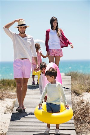 family with five children - Children with their parents holding inflatable rings on a boardwalk on the beach Stock Photo - Premium Royalty-Free, Code: 6108-06907553