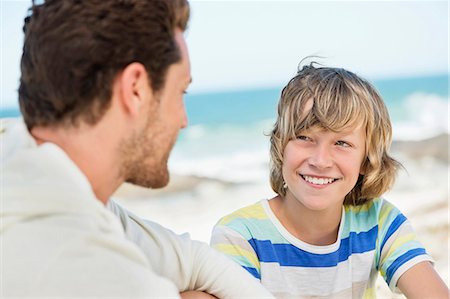 preteen boy beach - Man sitting with his son on the beach Stock Photo - Premium Royalty-Free, Code: 6108-06907571