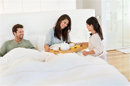 Girl serving tea to her parents on the bed Stock Photo - Premium Royalty-Free, Code: 6108-06907646