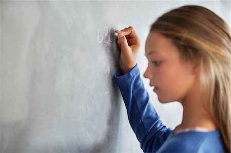 Close-up of a girl writing on a blackboard in a classroom Foto de stock - Sin royalties Premium, Código: 6108-06907677