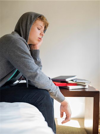 Teenage boy sitting on the bed and thinking Stock Photo - Premium Royalty-Free, Code: 6108-06907686