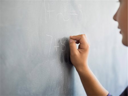 Close-up of a boy writing on a blackboard in a classroom Photographie de stock - Premium Libres de Droits, Code: 6108-06907699