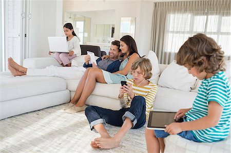 family living room devices - Family using electronics gadget Stock Photo - Premium Royalty-Free, Code: 6108-06907615