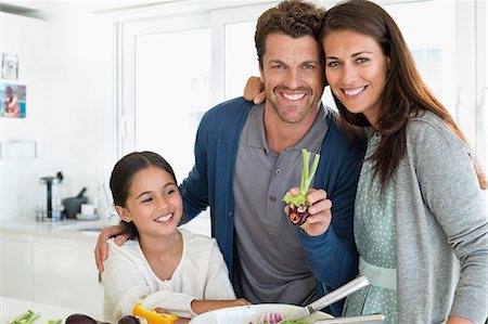 family looking at camera indoor - Couple with their daughter enjoying in the kitchen Stock Photo - Premium Royalty-Free, Code: 6108-06907627