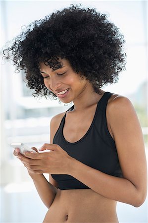 Smiling woman text messaging on a mobile phone Stock Photo - Premium Royalty-Free, Code: 6108-06907792