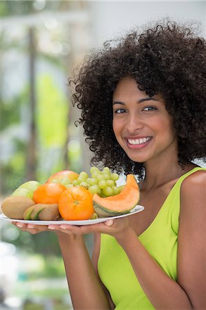 Smiling woman holding a plate of fruits Foto de stock - Sin royalties Premium, Código: 6108-06907799