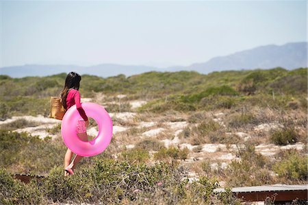 simsearch:6108-06907307,k - Woman holding an inflatable ring and walking on a boardwalk on the beach Stock Photo - Premium Royalty-Free, Code: 6108-06907722
