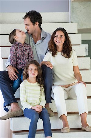 family at home white - Family sitting on steps and smiling Stock Photo - Premium Royalty-Free, Code: 6108-06907825