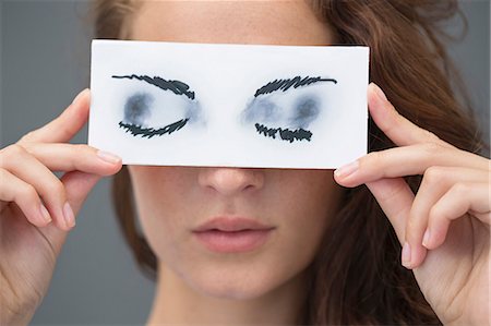 simsearch:6108-06908066,k - Woman holding a paper with false eyes in front of her face Stock Photo - Premium Royalty-Free, Code: 6108-06908067