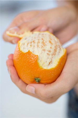 Close-up of a woman's hand peeling an orange Foto de stock - Royalty Free Premium, Número: 6108-06908068