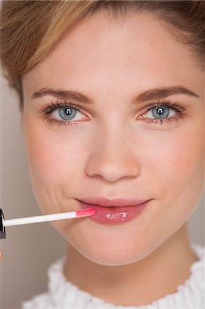 simsearch:6108-07969479,k - Portrait of a beautiful woman applying lip gloss Foto de stock - Sin royalties Premium, Código: 6108-07969468