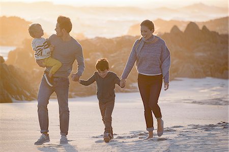 family holding hands on beach at sundown - Happy young family walking on the beach at sunset Stock Photo - Premium Royalty-Free, Code: 6108-08662293