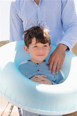 Happy father and son with rubber ring on beach Stock Photo - Premium Royalty-Free, Code: 6108-08662384