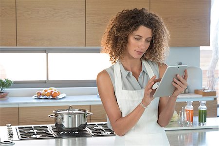 Young woman using a digital tablet in the kitchen Stock Photo - Premium Royalty-Free, Code: 6108-08662490