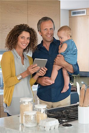 family husband wife images - Couple using digital tablet with their daughter in the kitchen Stock Photo - Premium Royalty-Free, Code: 6108-08662497