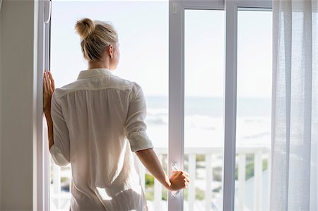 Young woman standing by window at home Photographie de stock - Premium Libres de Droits, Code: 6108-08662420