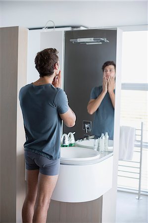 Young man applying aftershave on her face Photographie de stock - Premium Libres de Droits, Code: 6108-08662548