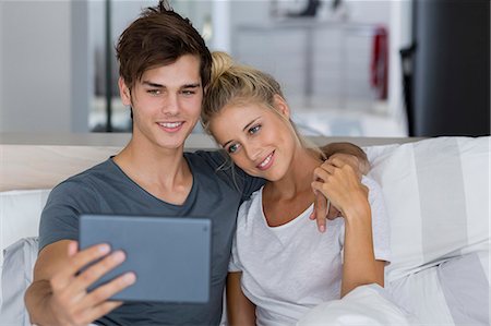 simsearch:6108-06166423,k - Young couple taking a selfie on the bed Fotografie stock - Premium Royalty-Free, Codice: 6108-08662530