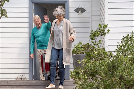 Happy senior man waving to his wife with suitcase on staircase Foto de stock - Sin royalties Premium, Código: 6108-08662744