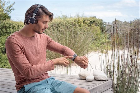 simsearch:6108-08725387,k - Young man using his smart watch and listening to music with headphones Stock Photo - Premium Royalty-Free, Code: 6108-08662725