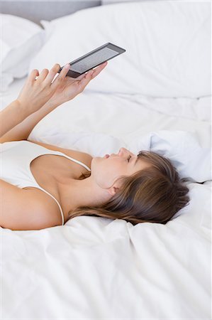 reading on bed - Woman lying on the bed using a digital tablet Stock Photo - Premium Royalty-Free, Code: 6108-08662886