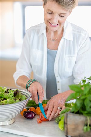 simsearch:695-03378918,k - Happy senior woman cutting vegetables in kitchen Fotografie stock - Premium Royalty-Free, Codice: 6108-08662800