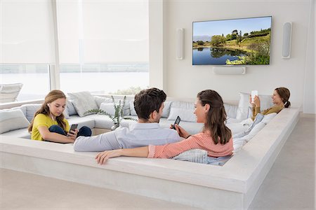 Couple watching television with their children busy in different activities Stock Photo - Premium Royalty-Free, Code: 6108-08662943
