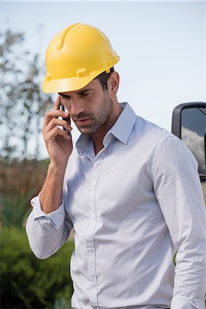 Male engineer talking on a mobile phone at site Stock Photo - Premium Royalty-Free, Code: 6108-08662947