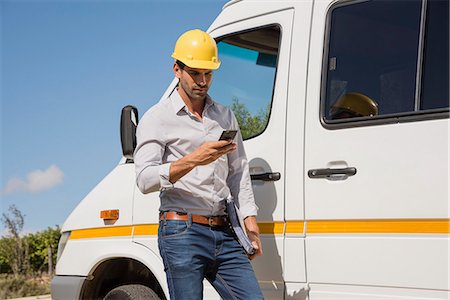 Male engineer using a mobile phone by van at site Stock Photo - Premium Royalty-Free, Code: 6108-08662944
