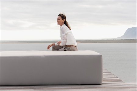 deck lake - Happy mature woman sitting on ottoman at lakeshore Stock Photo - Premium Royalty-Free, Code: 6108-08662916