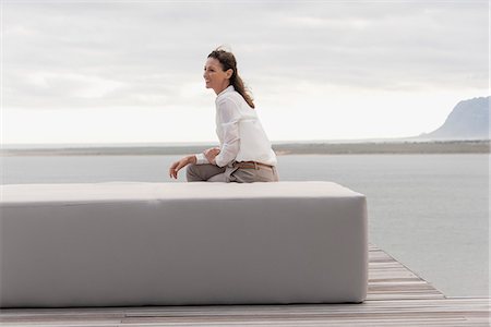 Happy mature woman sitting on ottoman at lakeshore Photographie de stock - Premium Libres de Droits, Code: 6108-08662916