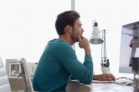 person sitting in chairs at desk side view - Young businessman working on computer in an office Stock Photo - Premium Royalty-Free, Code: 6108-08663005