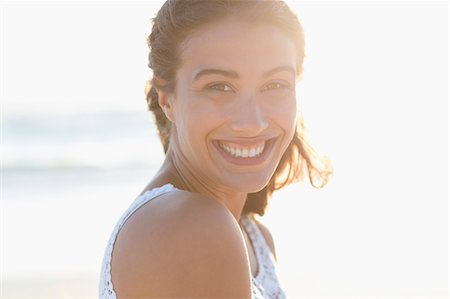 Portrait of a beautiful young woman smiling on the beach Stock Photo - Premium Royalty-Free, Code: 6108-08663031