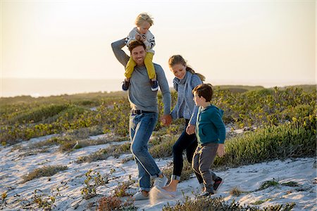 parent and child and outside and sky - Happy young family walking on the beach at sunset Stock Photo - Premium Royalty-Free, Code: 6108-08663181
