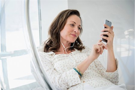 simsearch:6108-08663336,k - Mature woman listening to music with smart phone in chair Stockbilder - Premium RF Lizenzfrei, Bildnummer: 6108-08663198