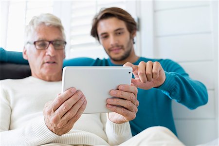 Happy father and son using digital tablet in living room Photographie de stock - Premium Libres de Droits, Code: 6108-08663119