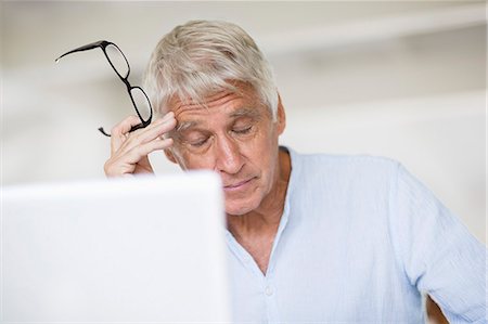 displeased - Tired senior man head in hand with laptop on table Stock Photo - Premium Royalty-Free, Code: 6108-08663132