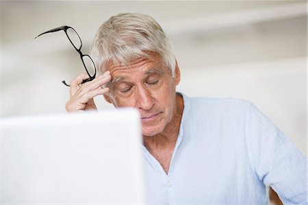 senior stress home - Tired senior man head in hand with laptop on table Stock Photo - Premium Royalty-Free, Code: 6108-08663132