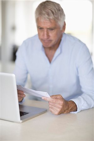 simsearch:6108-08663281,k - Senior man reading a letter with laptop on table Photographie de stock - Premium Libres de Droits, Code: 6108-08663137