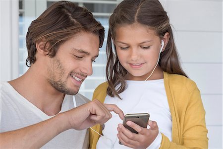 simsearch:6108-06167284,k - Happy father with his little daughter listening to music on mobile phone with earbuds Foto de stock - Sin royalties Premium, Código: 6108-08663284