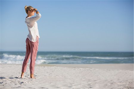 simsearch:6108-08662619,k - Beautiful young woman standing on sunny beach Stock Photo - Premium Royalty-Free, Code: 6108-08663217