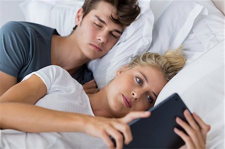simsearch:6108-06166423,k - Young woman using a digital tablet with her boyfriend sleeping near her Fotografie stock - Premium Royalty-Free, Codice: 6108-08663220