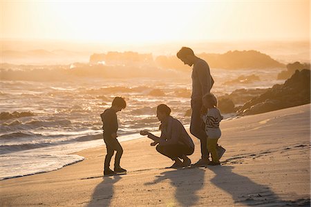 Happy young family enjoying on the beach at sunset Stock Photo - Premium Royalty-Free, Code: 6108-08663340