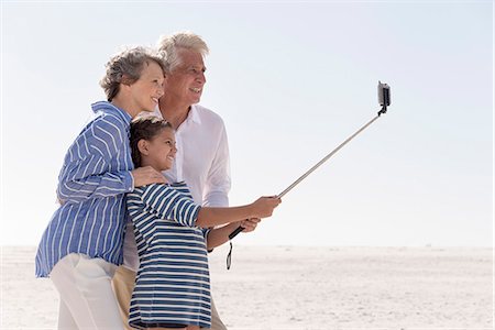 Happy grandparents with granddaughter taking selfie together on beach Stock Photo - Premium Royalty-Free, Code: 6108-08663398