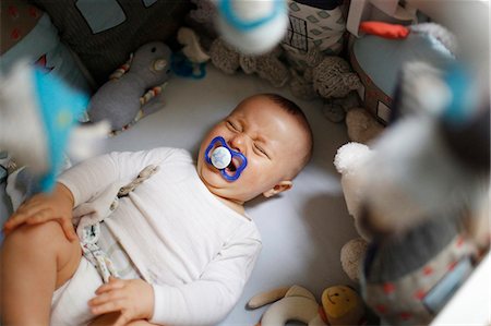 sad person laying down - 8 months baby boy crying in his bed Stock Photo - Premium Royalty-Free, Code: 6108-08636840