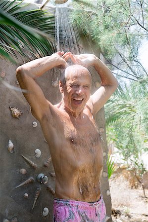 senior man happy portrait - Greece, Cyclades, smiling man taking a shower at the beach Stock Photo - Premium Royalty-Free, Code: 6108-08637046
