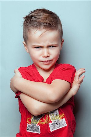 sulking arms folded - Portrait of an angry boy with arms crossed, looking toward the lens Stock Photo - Premium Royalty-Free, Code: 6108-08637399